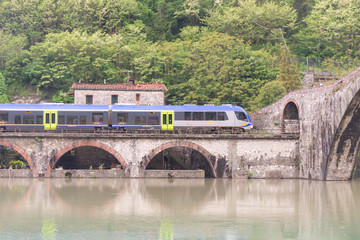 Bridge of a devil. Bridge over the river in Tuscany. Built in the 11 century. The train passes under the bridge.