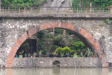 Bridge of a devil. Bridge over the river in Tuscany. Built in the 11 century. Pots with plants under the railway bridge.