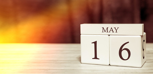 Calendar reminder event concept. Wooden cubes with numbers and month on May 16 with sunlight.