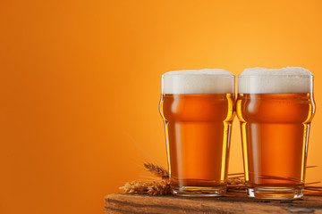 Glasses of beer on table against color background