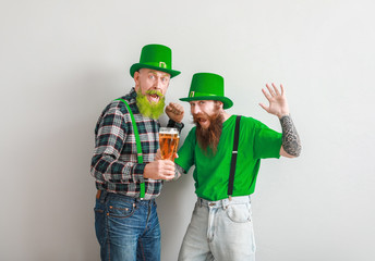 Bearded men with glasses of beer on light background. St. Patrick's Day celebration
