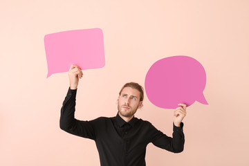 Young man with different blank speech bubbles on color background