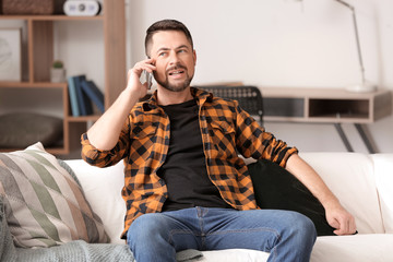 Mature man talking by phone at home