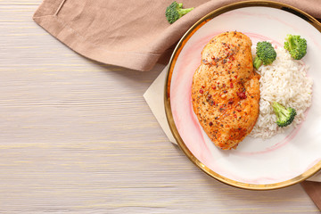 Plate with tasty rice and chicken on table