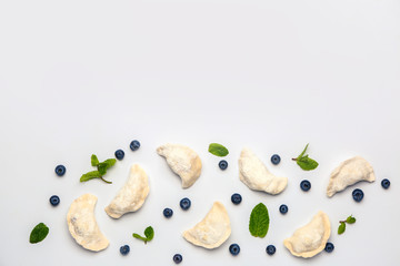 Raw dumplings with blueberries on white background