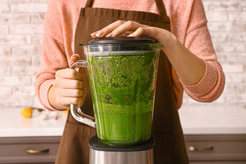 Woman preparing healthy pesto sauce in kitchen