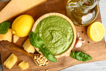 Pesto sauce in bowl with ingredients on table