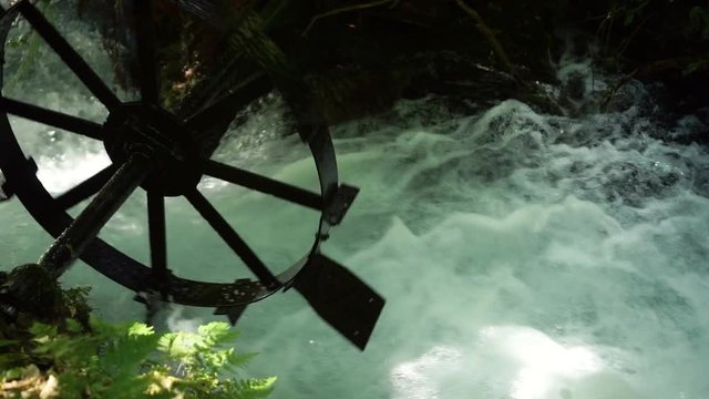 Detail shot of old rustic water mill wheel in pristine clear fast flowing creek Putaruru Blue Spring, New Zealand