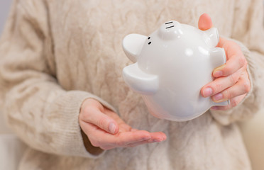 Woman is shaking piggy bank. Financial problem