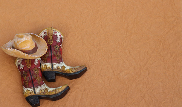 cowboy boots and hat laying on a textured brown background with writing space