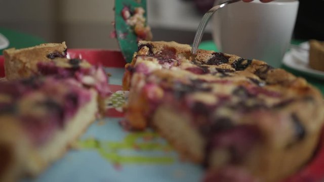Woman's hands cut berry pie on the table