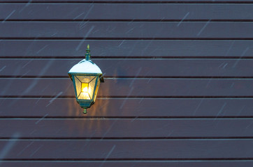 A burning lantern on the wall of the house.Lamp on the building. Lamp on the wall of the building.