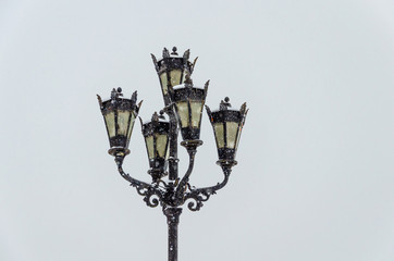 Fototapeta na wymiar Lights and lanterns on a pole on a winter day under snow.