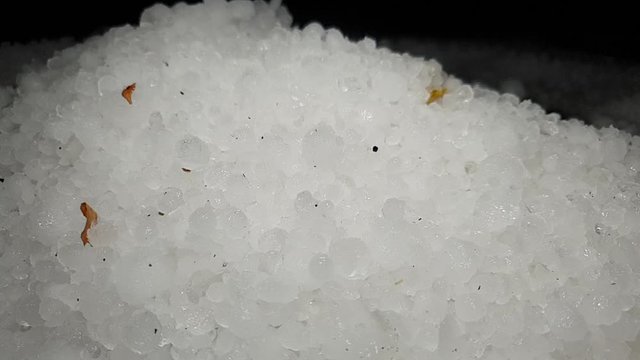 White hail storm ice balls being shoveled and moved in a pile for cleanup and removal