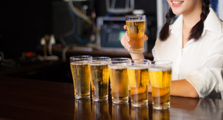 Female waiters hold a glass of beer and serve beer at the counter.