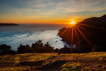 Sun setting into the Pacific Ocean beyond San Francisco Bay, viewed from Marin Headlands in California, sun burst effect