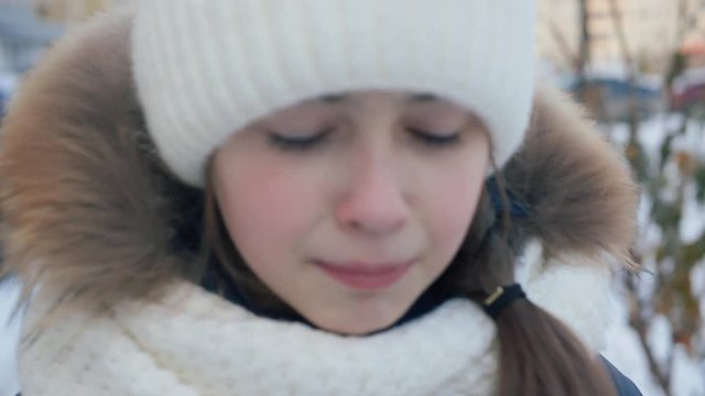 Portrait upset young girl crying on winter street. Close up face unhappy girl crying on winter walk at snowy city street
