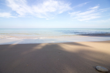 Fototapeta na wymiar Das rugige Meer an einem wunderschönen Sandstrand verschwimmt mit dem blauen Himmel