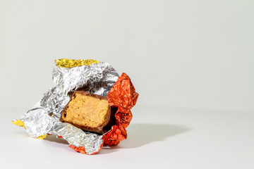 Bitten chocolate candy with a filling in a foil wrapper. Halva in chocolate coating.