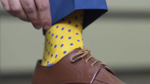 Man putting Tying Brown Dress Shoes with Yellow Socks