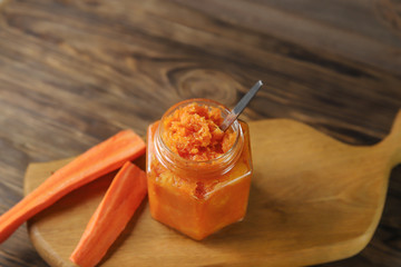Homemade carrot jam in glass jar on brown wooden background. Healthy sweet sauce
