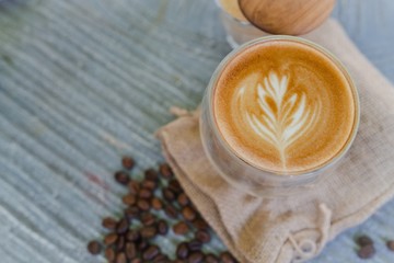Glass of hot coffee with beautiful latte art on stone table decorated with roasted coffee bean background, Top view. Copy space