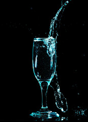 blue water with splashes in a glass on a black background