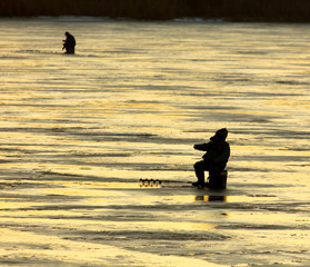 Fishermen fish on ice at dawn