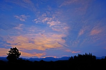 Beautiful sunset sky and cloud with silhouette trees and mountain as foreground. 