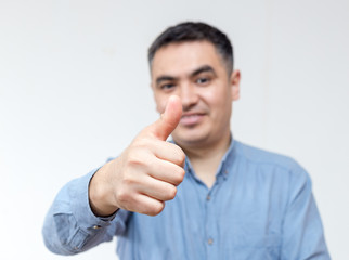 Portrait of a man in a blue shirt shows thumb up on a white background