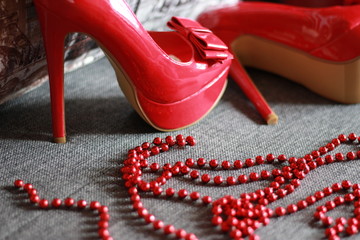 Red high-heeled shoes with beads with a pillow and on the sofa