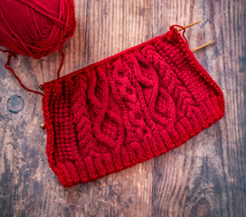  Flat lay of red knitted project and work in progress on a hard wood floor