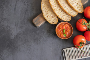 Top view of popular Spanish tapa, Crusty bread with fresh tomato or pan con tomate on dark concrete backgropund with copy space.