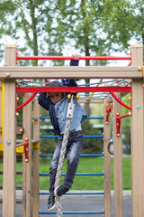 brave boy playing on the playground and going down with ropes down