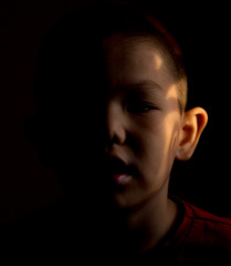 Portrait of little smiling boy. Sunset warm light inside the house