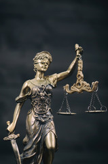 Scales of Justice, Justitia, Lady Justice on a black wooden background.