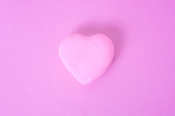 розовое сердце на розовом фоне. сердце расположено в центре кадра.