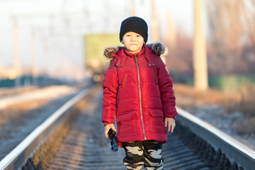 a boy crossing a railway in a red jacket