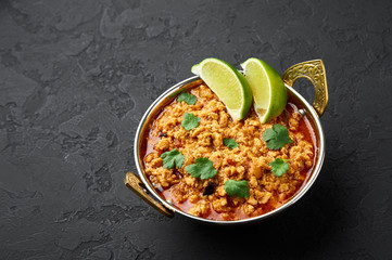 Chicken keema in traditional indian copper kadai at dark slate background. Kheema is indian and pakistani cuisine curry dish with minced meat and spices.