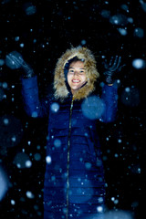 young girl at night in jackets on the background of snowfall