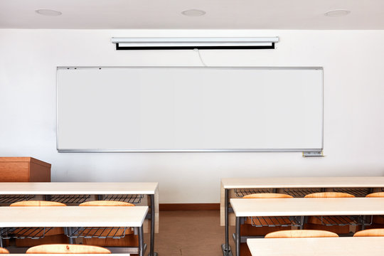 Classroom interior with white board and wooden desks