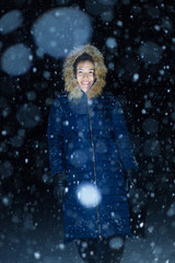 young girl at night in jackets on the background of snowfall