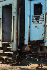 Vandalism on the railway. Vandalism concept. Train vandalism. Broken windows of blue old rusty train. Broken train compartments. Abandoned train car doorway and window detail.