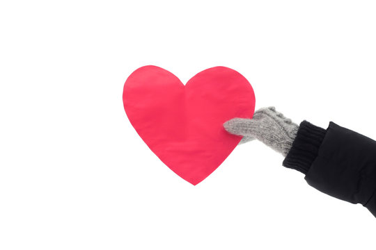 Female hand in gray mittens holds a big red heart.  Winter romantic mood. Stock photo for valentine's day. Celebration background for web, print and wallpaper.  