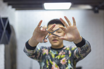 Portrait of a cheerful, joyful barber with scissors, tools in his hands, looking at the camera