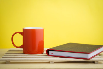 an empty pastel color mug with dollar bills and a planner with a retro clock