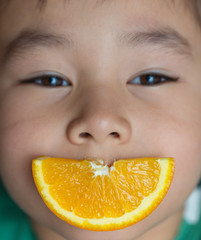 boy eating orange and lips smiling
