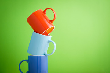 Risk management concept. the pile of colorful pastel color ceramic mugs on green background