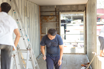 Fototapeta premium Sheathing, insulation of the container. Workers insulate an iron container for a residential building