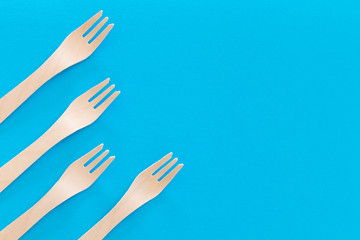 Fork setup Cutlery pattern on a bright blue background. Eco-friendly wooden disposable cutlery on bright backdrop. Wallpapers for modern and ecological food. Plastic Free background for food banner